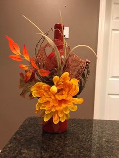 a vase filled with orange flowers on top of a granite counter next to a door