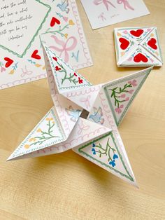 an origami star on a table with cards and envelopes next to it