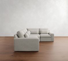 a white couch sitting on top of a wooden floor next to a chair and ottoman