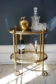 a gold bar cart with wine glasses on it