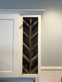 a wine rack in the corner of a kitchen cabinet with an arrow design on it