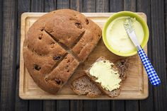 a wooden cutting board topped with bread and butter