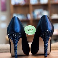 a pair of black high heeled shoes sitting on top of a wooden table next to a book shelf