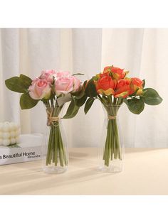 three vases with roses in them on a table next to a book and candle