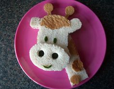 a pink plate topped with two pieces of bread shaped like a cow's head