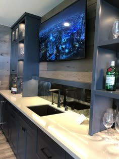 a large flat screen tv mounted to the side of a wall above a kitchen sink