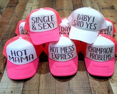 pink and white hats with the words hot mess problems printed on them sitting on a wooden floor