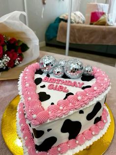 a heart shaped cake with pink frosting and black dots on the top is sitting on a gold plate