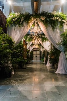 an indoor wedding venue with white drapes and greenery