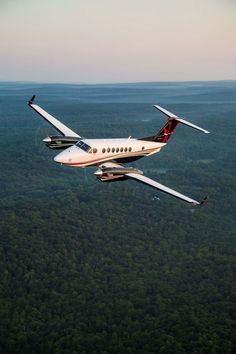 an airplane flying in the sky over some trees