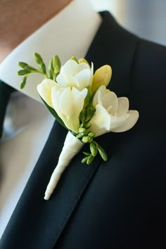 a boutonniere with white and yellow flowers on the lapel of a man