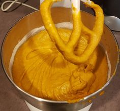 a metal bowl filled with yellow batter and two pretzels sticking out of it