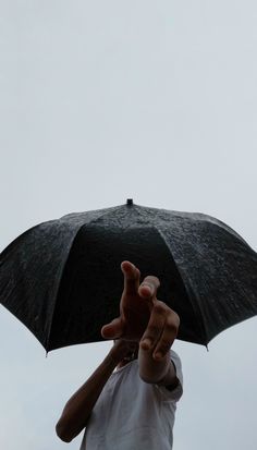 a person holding an umbrella up in the air with their hand on top of it