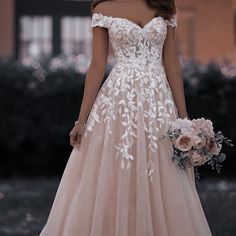 a woman in a wedding dress with flowers on her bouquet is standing outside at night