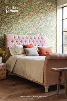 a pink bed sitting in the middle of a bedroom next to a wooden table and chair