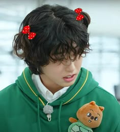 a person wearing a green hoodie with red bows and a teddy bear on it