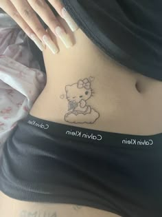 a hello kitty tattoo on the side of a woman's stomach