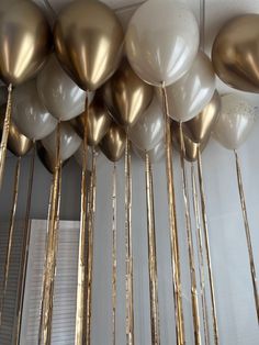 gold and white balloons are hanging from the ceiling