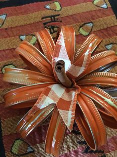 an orange and white flower made out of duct tape sitting on top of a rug