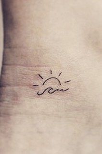 a small sun tattoo on the side of a woman's stomach that reads sou