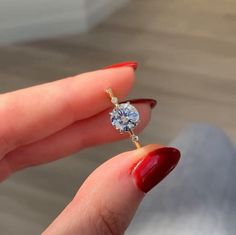 a woman's hand holding an engagement ring with a diamond on the middle finger