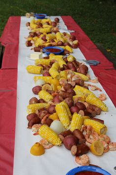 corn on the cob, potatoes and shrimp are laid out on a long table