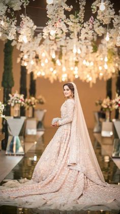 a woman in a wedding dress standing under chandelier