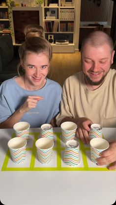 two people sitting at a table with cups in front of them