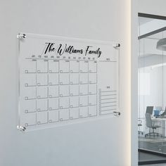 a glass calendar hanging on the wall in front of a whiteboard with black writing that says, the williams family