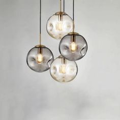 three clear glass globes hanging from a ceiling fixture with brass fittings and lightshades