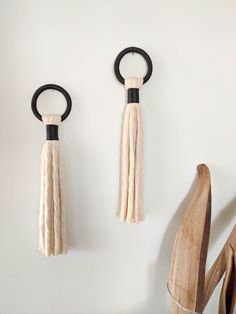 two pieces of wood are hanging on the wall with black rings and tassels