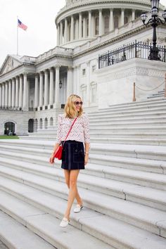 a woman standing on steps in front of the capital building with her purse and handbag