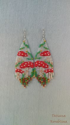 a pair of beaded earrings with red, green and white beads hanging from them