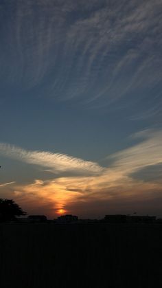 the sun is setting behind some clouds in the sky