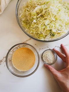 two bowls with different types of food in them on a counter top next to a person's hand