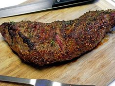 a piece of meat on a cutting board next to a knife