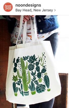 a white bag with green cactus designs on it and a person holding the bag in their hand