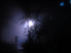 a person walking down a dark street at night with the moon in the sky behind them