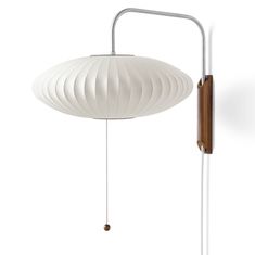 a white lamp hanging from the ceiling next to a wooden pole with a light fixture on it