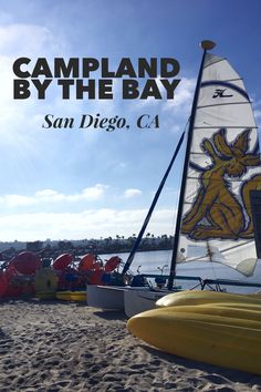 a sailboat sitting on top of a sandy beach next to the ocean with text reading campland by the bay san diego, ca