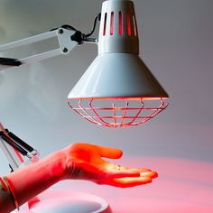 a person's hand reaching for a light that is on top of a table