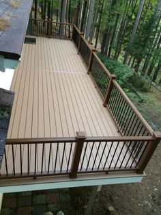 a deck in the middle of a wooded area with stairs leading up to an upper level