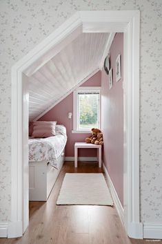 an attic bedroom with pink walls and floral wallpaper on the walls, along with a white rug