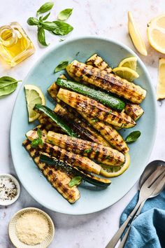 grilled zucchini and green beans on a blue plate with lemons, salt and pepper