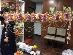 a woman standing in front of a flower decorated arch with beads and flowers on it