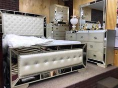 a white bed sitting on top of a wooden floor next to a dresser and mirror