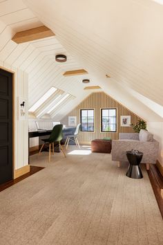 an attic living room with white walls and wood trimming on the ceiling, carpeted floor