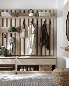 a wooden bench sitting next to a wall filled with coat racks and coats hanging on it