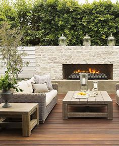 an outdoor living area with couches, tables and a fire place in the center