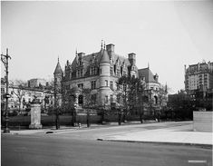 an old black and white photo of a large building on the corner of a street